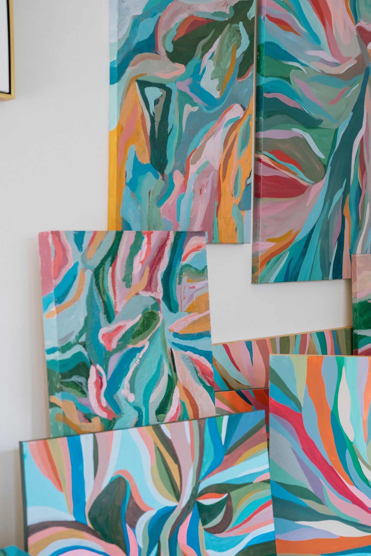 Set of abstract art pieces with vibrant colors on a white wall.
